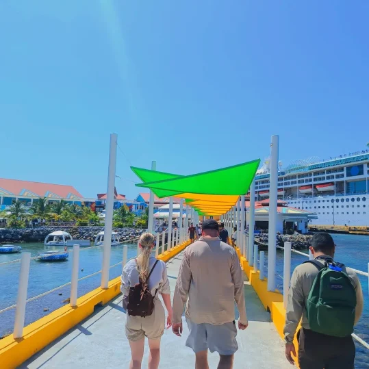 Cruise passengers walking the pier to a ship at Port of Roatan